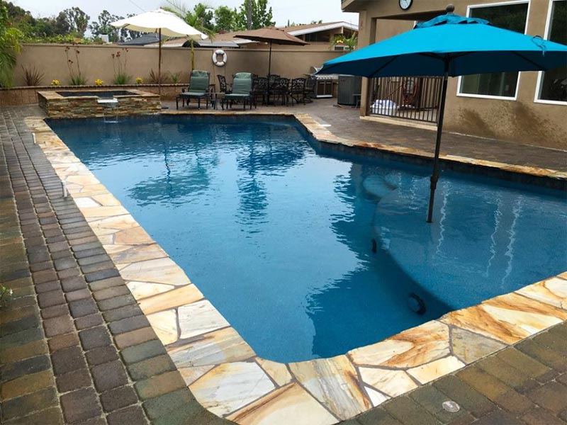 A pool with an umbrella in a backyard
